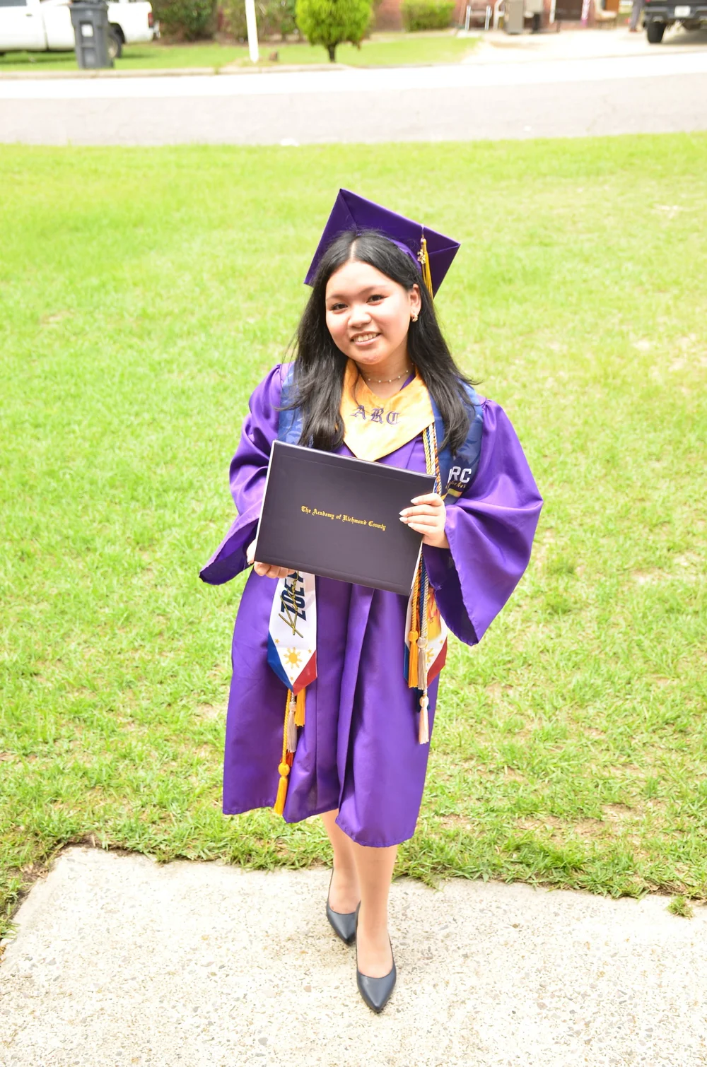 Zoey Francisco in her graduation cap and gown holding her diploma